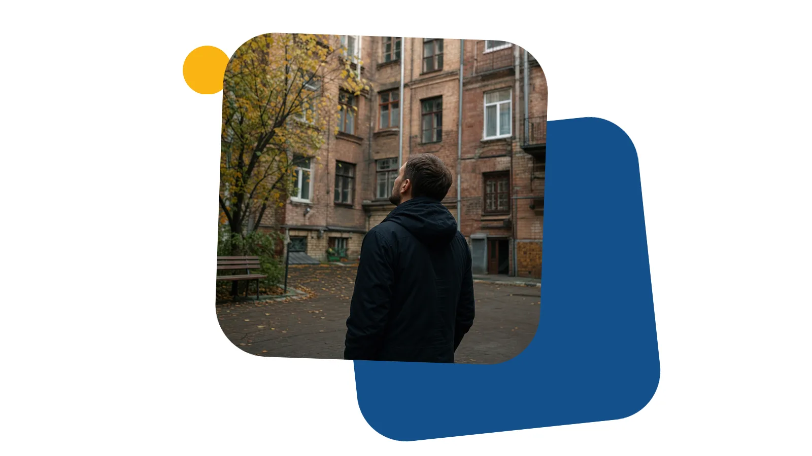 Чоловік у куртці стоїть у дворі старого київського будинку і дивиться вгору на вікна