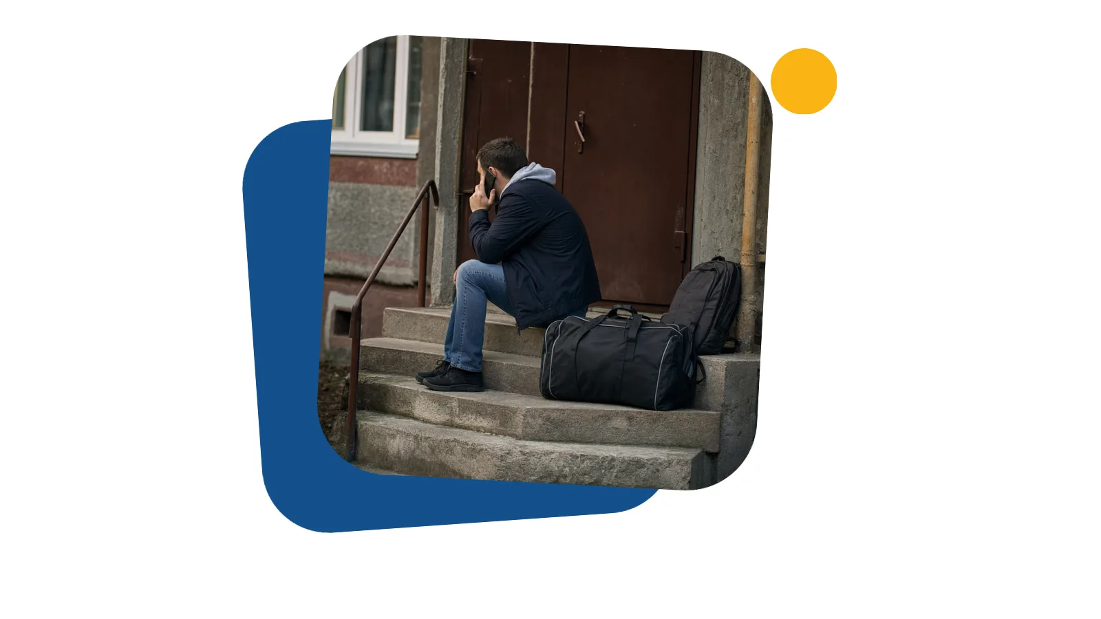 Чоловік сидить на сходах під'їзду з телефоном біля вуха і дорожньою сумкою поруч